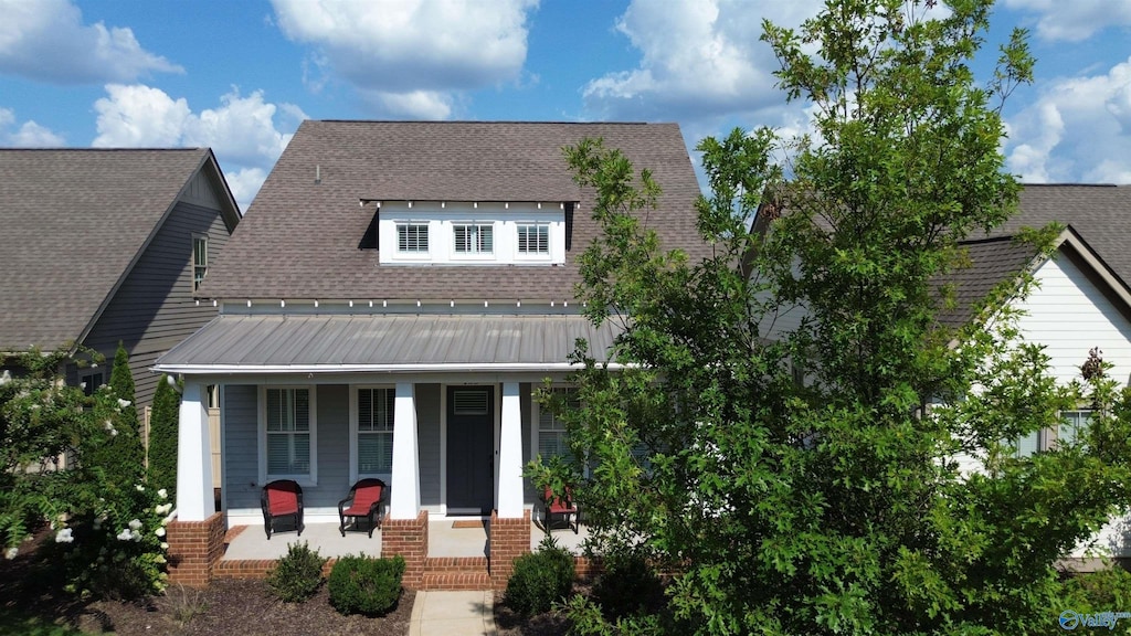 view of front of house featuring a standing seam roof, covered porch, a shingled roof, and metal roof