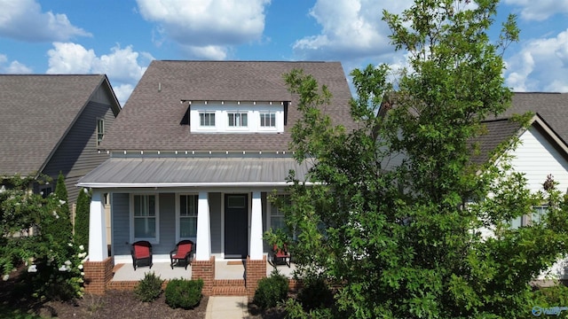 view of front facade with a standing seam roof, a porch, a shingled roof, and metal roof