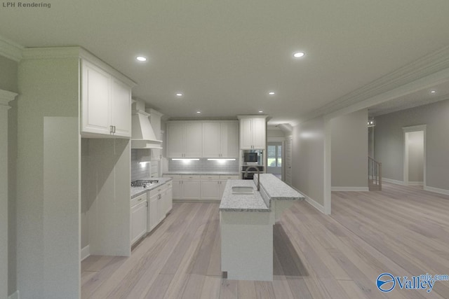 kitchen with light stone countertops, white cabinetry, tasteful backsplash, premium range hood, and a kitchen island with sink