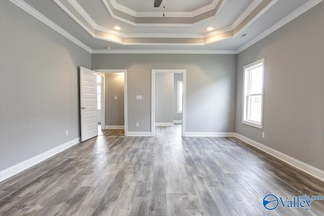 unfurnished bedroom with a raised ceiling, ornamental molding, and wood-type flooring