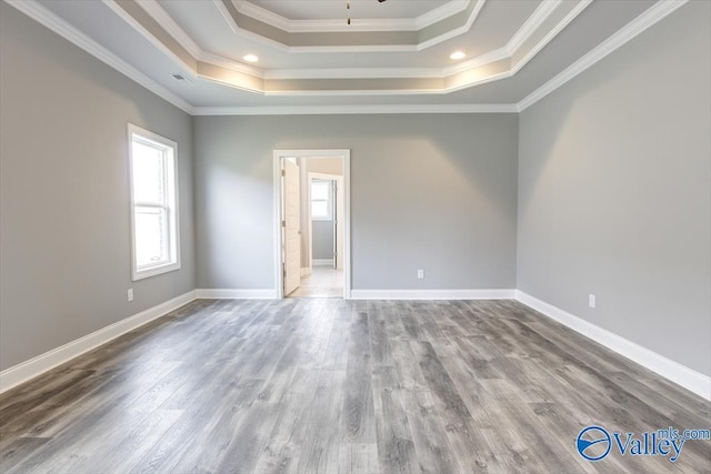 unfurnished room with wood-type flooring, a tray ceiling, and crown molding