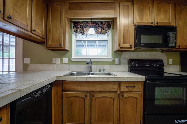 kitchen with tile counters, plenty of natural light, a sink, and black appliances