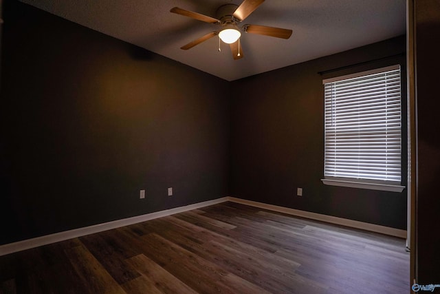 spare room featuring ceiling fan, baseboards, dark wood-type flooring, and a textured ceiling
