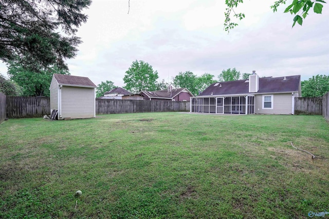 view of yard featuring a storage shed, a sunroom, an outbuilding, and a fenced backyard