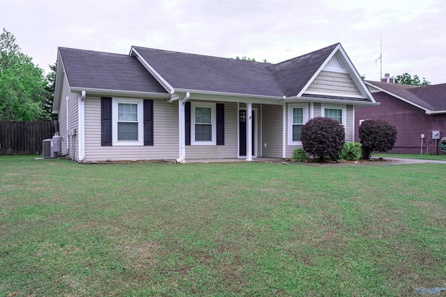 ranch-style house with roof with shingles, covered porch, a front yard, and central AC