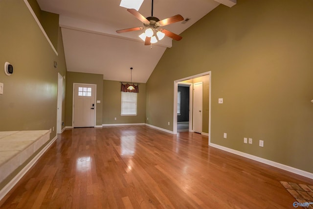 interior space with wood finished floors, a ceiling fan, beam ceiling, baseboards, and high vaulted ceiling