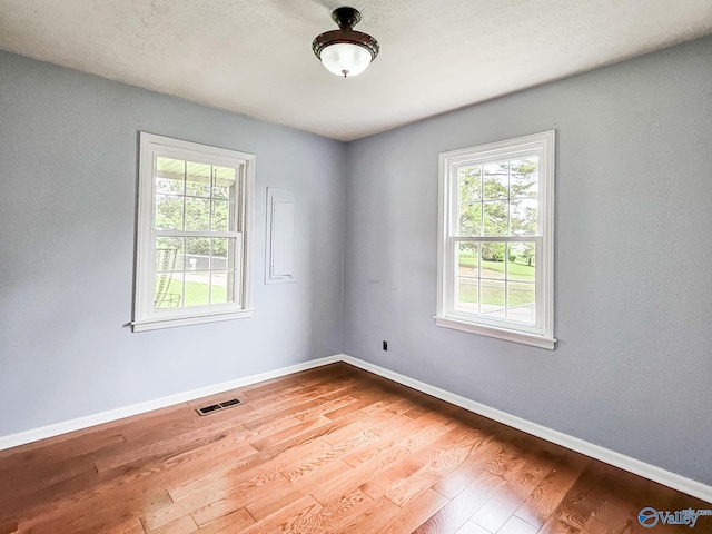 empty room featuring baseboards, visible vents, and wood finished floors