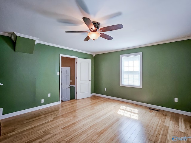 unfurnished bedroom featuring ceiling fan, visible vents, baseboards, light wood-style floors, and ornamental molding