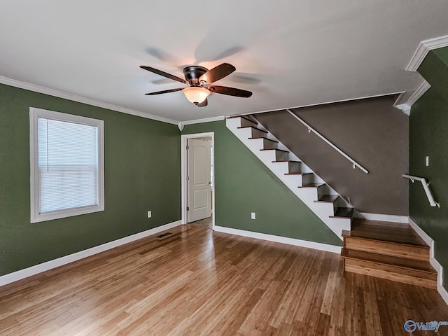 interior space featuring baseboards, stairway, wood finished floors, and crown molding