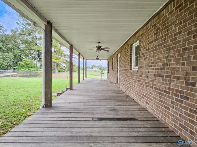 wooden terrace featuring fence, a ceiling fan, and a lawn