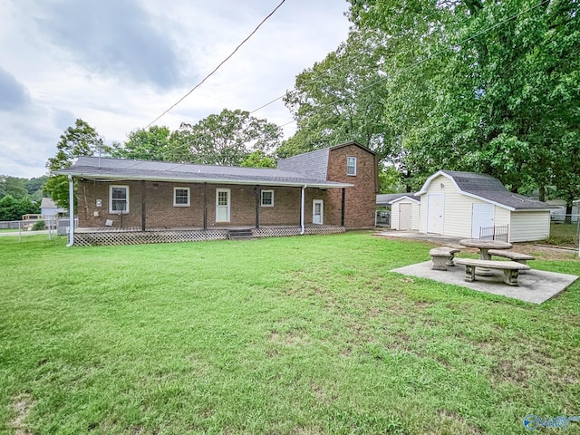 rear view of property featuring a lawn, a patio, an outbuilding, a shed, and brick siding