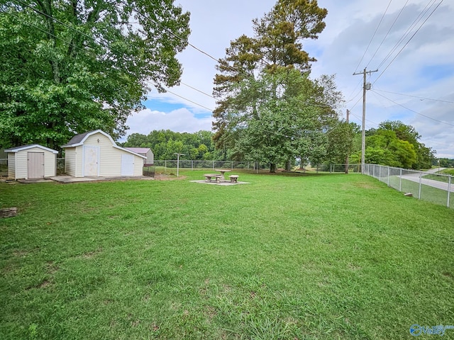 view of yard with a fire pit, a storage unit, an outdoor structure, and a fenced backyard