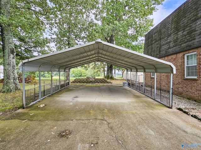 view of vehicle parking featuring fence, a carport, and concrete driveway