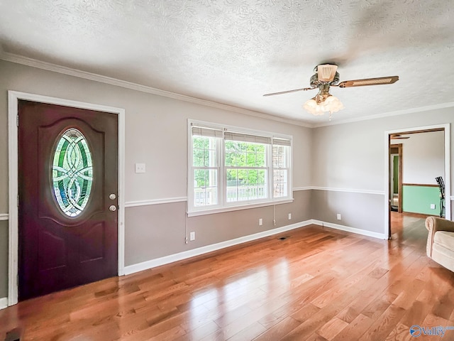 entrance foyer featuring ornamental molding, a ceiling fan, a textured ceiling, light wood-type flooring, and baseboards