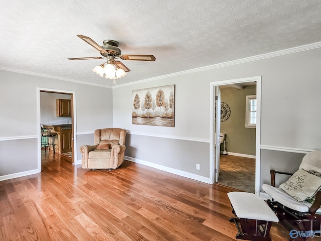 living area featuring a textured ceiling, wood finished floors, and crown molding