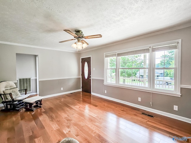 entryway with visible vents, crown molding, and wood finished floors