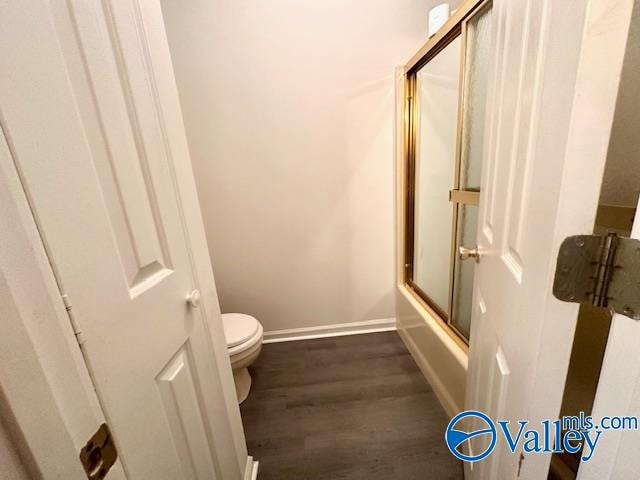 bathroom featuring toilet, enclosed tub / shower combo, and hardwood / wood-style flooring