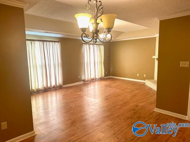 unfurnished room with hardwood / wood-style floors, ornamental molding, a chandelier, and a textured ceiling