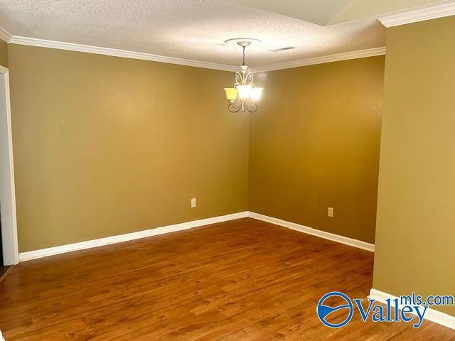 empty room with ornamental molding, hardwood / wood-style floors, a textured ceiling, and an inviting chandelier
