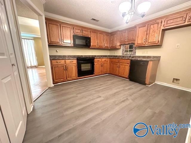kitchen with a textured ceiling, light hardwood / wood-style flooring, ornamental molding, black appliances, and sink