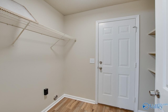 washroom featuring light wood-style flooring, baseboards, and hookup for an electric dryer