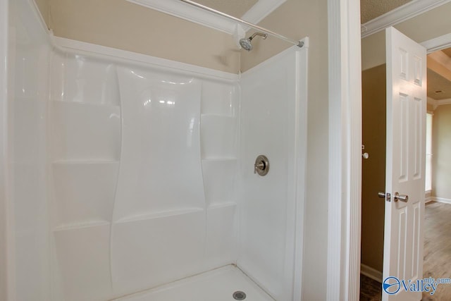 full bath with a shower, crown molding, and wood finished floors