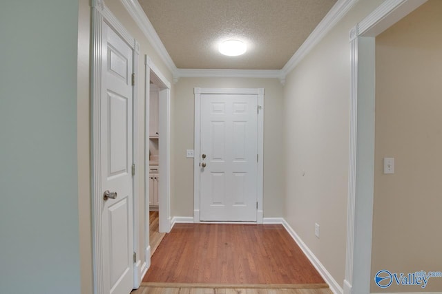 doorway to outside with light wood-style floors, a textured ceiling, ornamental molding, and baseboards