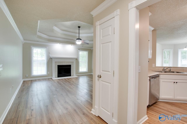 unfurnished living room featuring a sink, a textured ceiling, plenty of natural light, ceiling fan, and crown molding