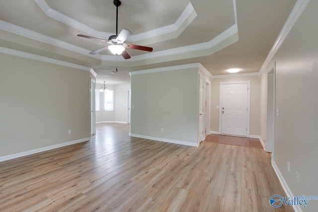 spare room featuring a raised ceiling, a ceiling fan, light wood-style floors, a chandelier, and crown molding