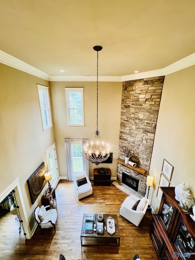 living room with hardwood / wood-style floors, a chandelier, crown molding, and a fireplace