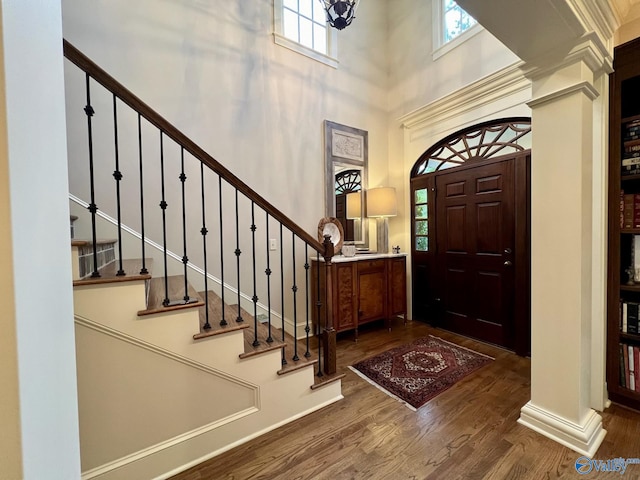 entrance foyer with a high ceiling, dark wood-type flooring, and a healthy amount of sunlight