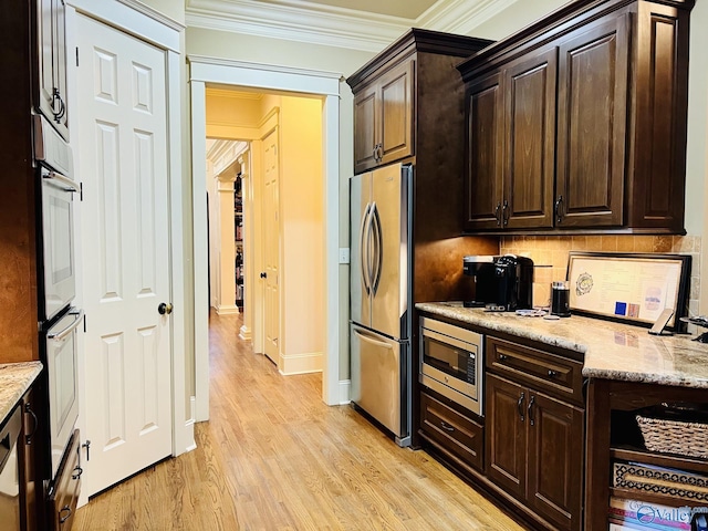 kitchen featuring light stone counters, appliances with stainless steel finishes, ornamental molding, backsplash, and light wood-type flooring