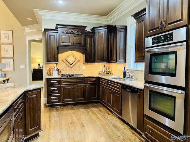 kitchen featuring backsplash, appliances with stainless steel finishes, light hardwood / wood-style floors, and crown molding