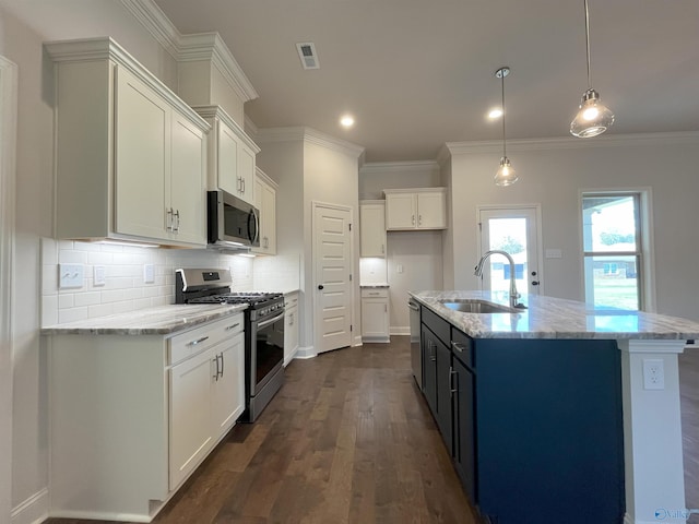 kitchen featuring appliances with stainless steel finishes, pendant lighting, sink, white cabinets, and a center island with sink