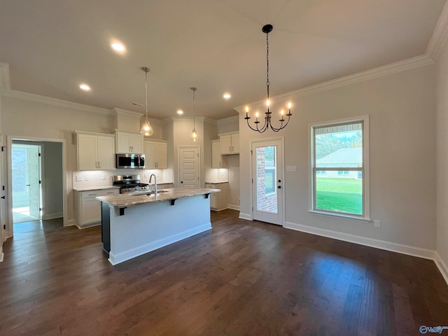 kitchen featuring appliances with stainless steel finishes, white cabinetry, hanging light fixtures, light stone countertops, and a center island with sink