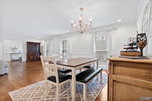 dining area with a chandelier, wood-type flooring, and ornamental molding