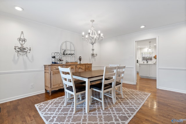 dining area with an inviting chandelier, dark wood-type flooring, and ornamental molding