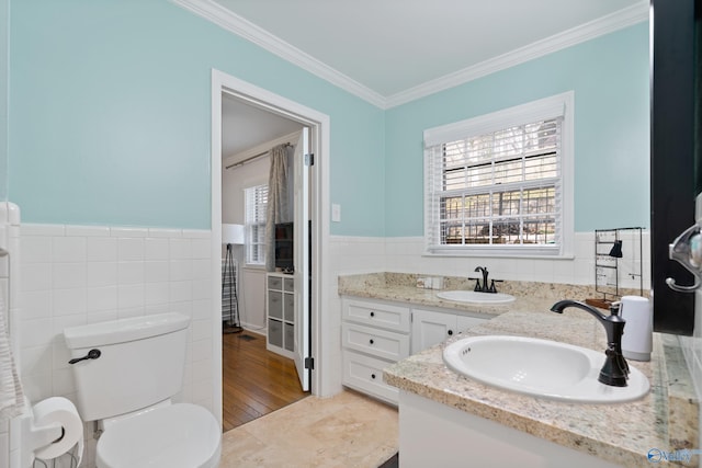 bathroom with tile patterned flooring, crown molding, toilet, vanity, and tile walls