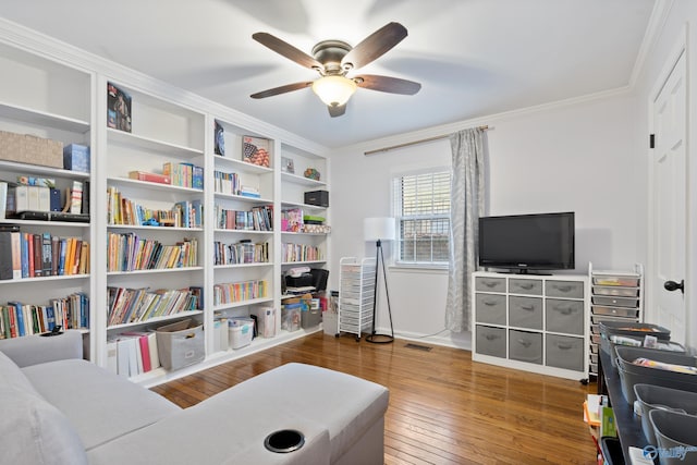 living area with hardwood / wood-style floors, ceiling fan, and ornamental molding