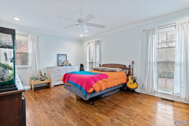 bedroom with multiple windows, ceiling fan, hardwood / wood-style floors, and crown molding