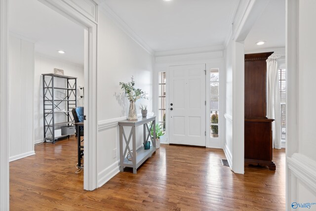 foyer with crown molding, a healthy amount of sunlight, and dark hardwood / wood-style floors