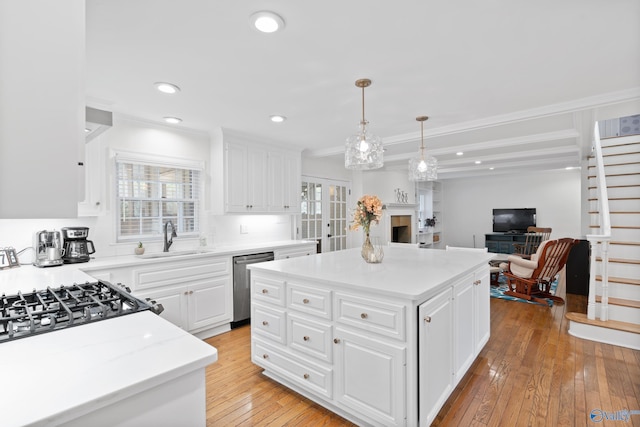 kitchen featuring a center island, sink, stainless steel dishwasher, white cabinets, and light wood-type flooring