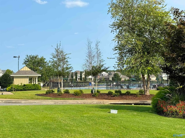 view of home's community with tennis court and a lawn