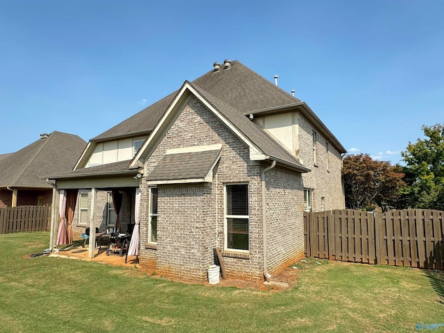 rear view of house featuring a lawn and a patio