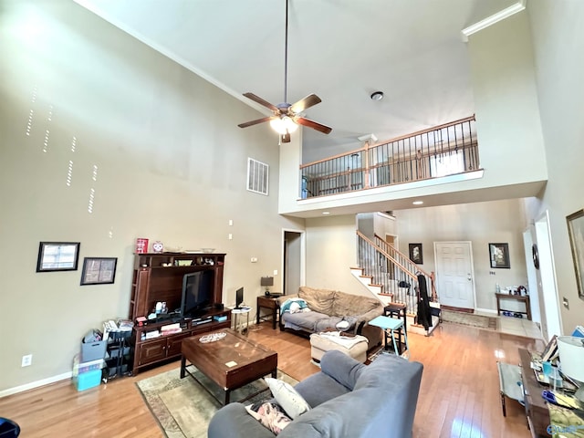 living room featuring a towering ceiling, light hardwood / wood-style floors, and ceiling fan