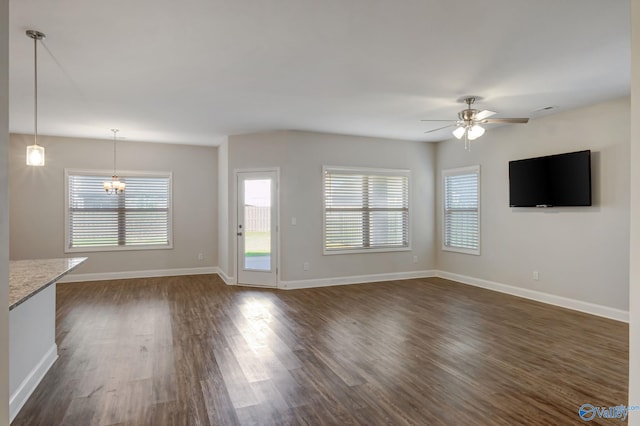 unfurnished living room with dark hardwood / wood-style floors and ceiling fan with notable chandelier