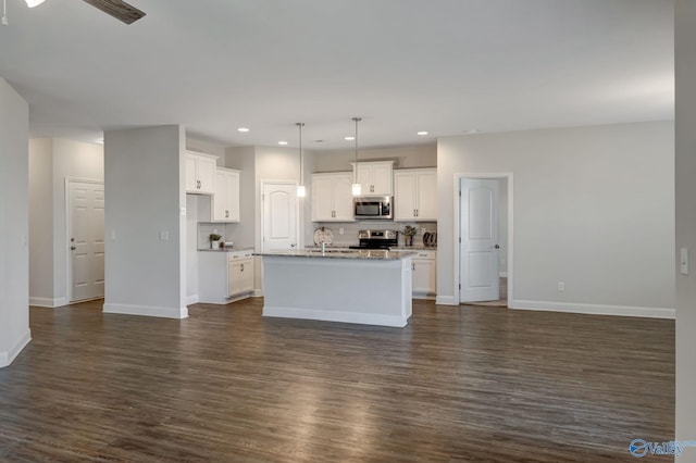 kitchen with appliances with stainless steel finishes, dark hardwood / wood-style flooring, and a center island with sink