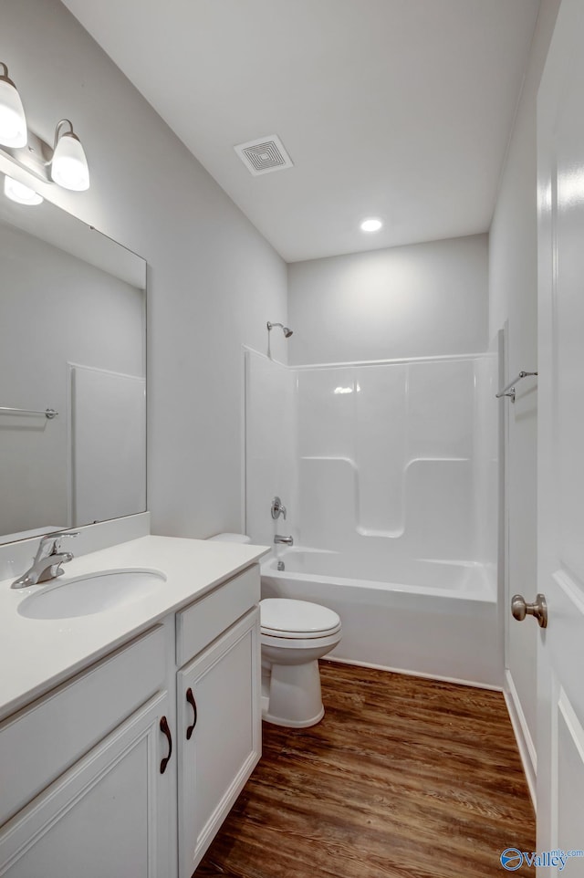 full bathroom with hardwood / wood-style floors, vanity, toilet, and  shower combination