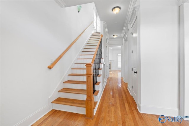 staircase featuring baseboards, ornamental molding, and wood finished floors