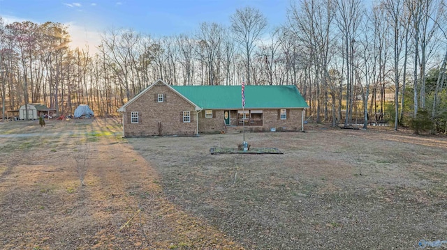 view of front of home featuring an outbuilding, brick siding, and a shed